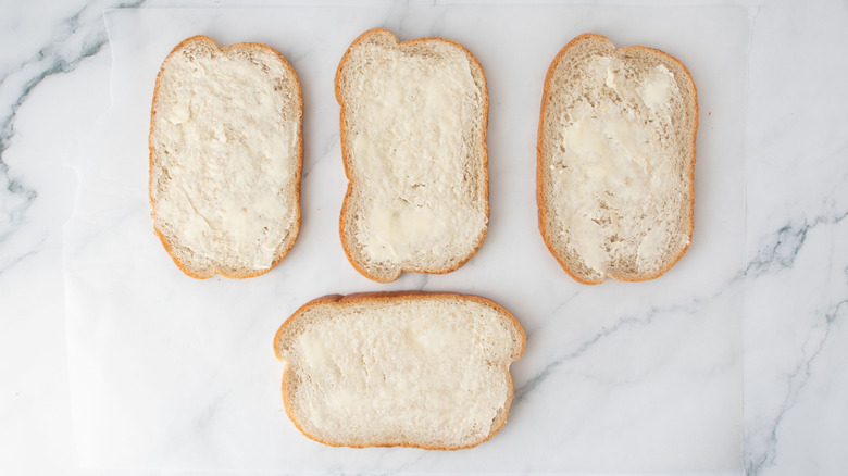 Buttered bread slices on wax paper