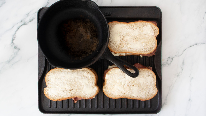 Sandwiches on grill pan with cast iron skillet on top