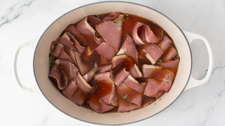 Pastrami slices and broth in large pot