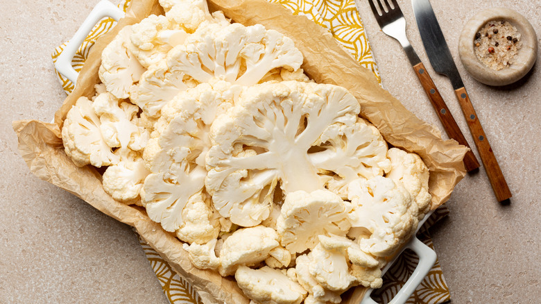 cauliflower slices on a baking dish with a fork and knife on the side