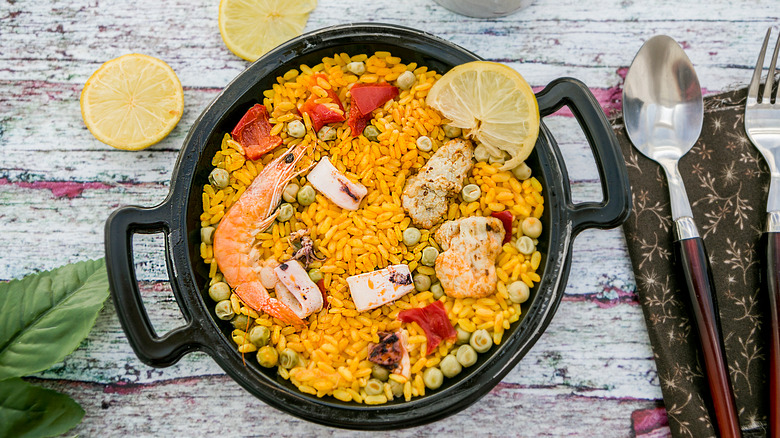 orange rice with vegetables and shrimp in black pot