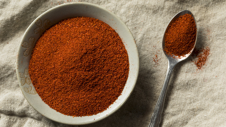 A spoon and bowl full of smoked paprika.