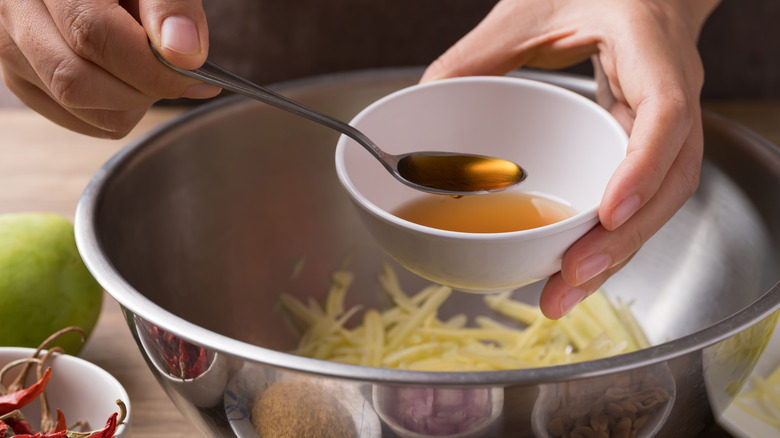 Adding fish sauce to a mango salad