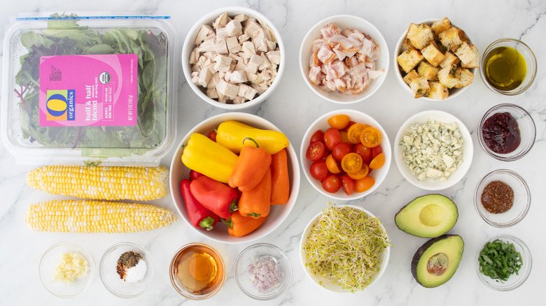vegetables, diced chicken, chopped bacon, and other rotisserie chicken and bacon salad ingredients laid out