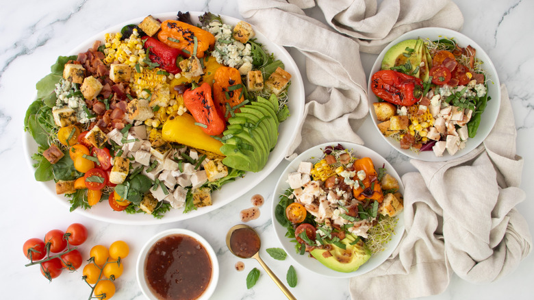 rotisserie chicken salad loaded with veggies, bacon, and raspberry dressing on a big platter and smaller plates