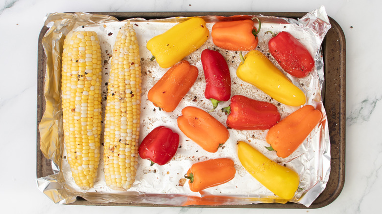 assorted vegetables seasoned on top of lined baking sheet