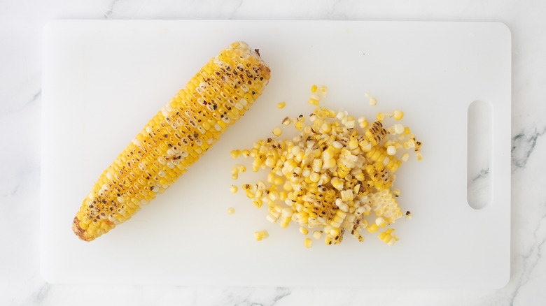 cob of corn with kernels sliced off on cutting board