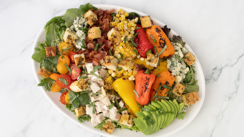 aerial view of a platter of rotisserie chicken salad loaded with veggies, bacon, and raspberry dressing