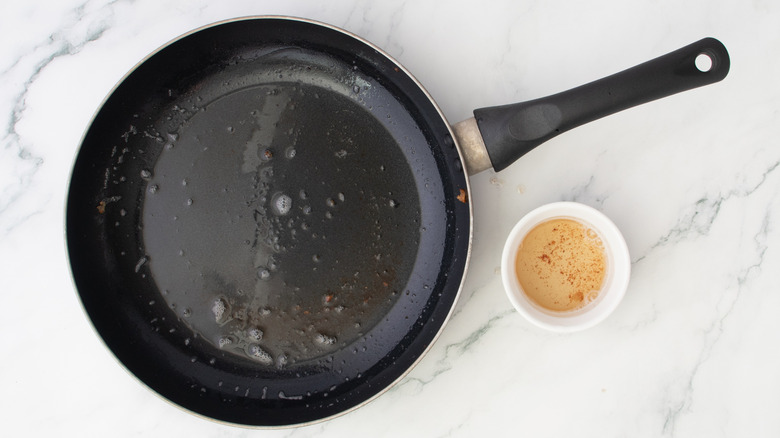 oily skillet next to bacon drippings in a small bowl