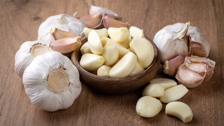 bowl of peeled garlic cloves with garlic bulbs