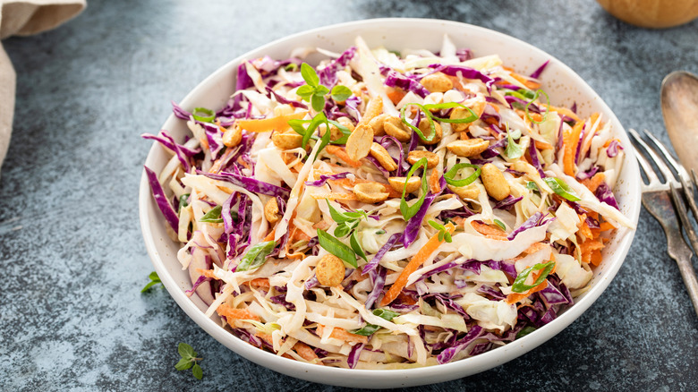 Coleslaw garnished with peanuts in a white bowl