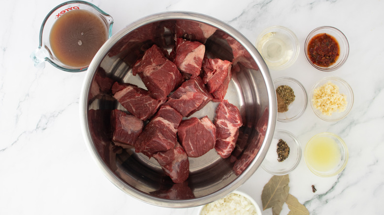 beef chunks in slow cooker pot surrounded by seasonings