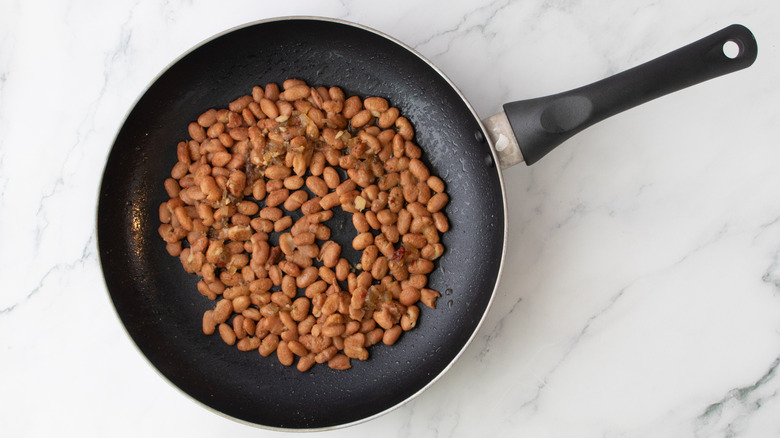 beans heating with pan drippings in skillet