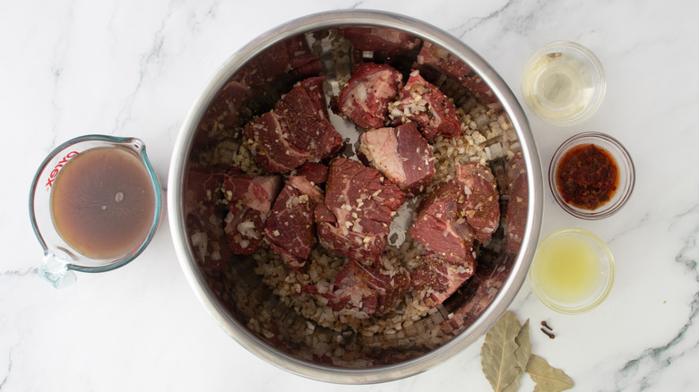 beef chunks with seasonings in slow cooker