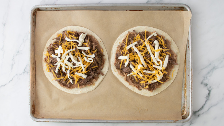 two tortillas topped with beans, beef, and cheese