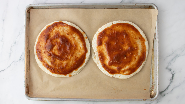 two tortillas topped with pizza sauce