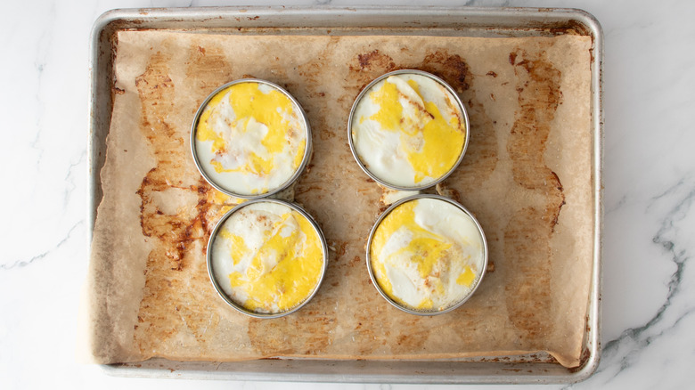cooked eggs inside ring molds in a baking pan