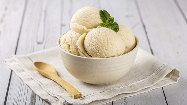 A big bowl of vanilla ice cream on a wooden table.