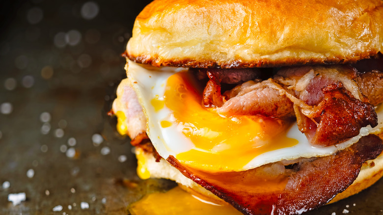 a breakfast sandwich with bacon and eggs