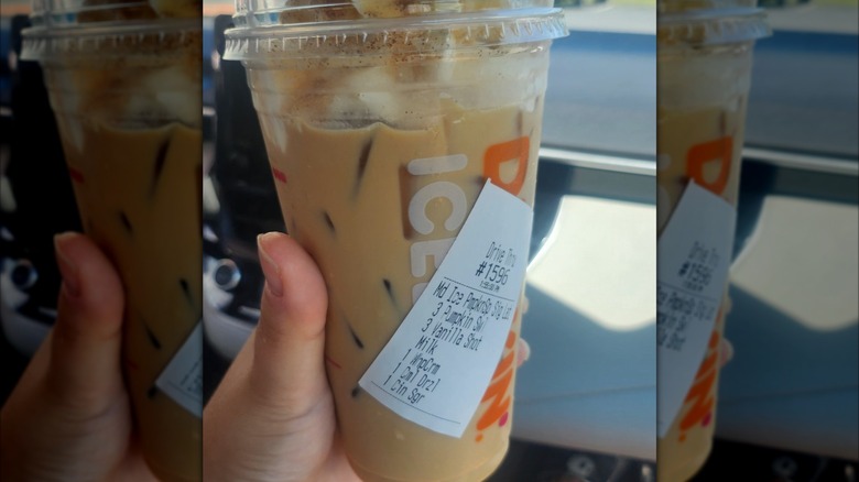 Hand holding a Dunkin' pumpkin latte