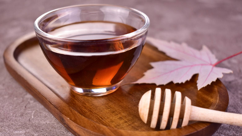 Maple syrup in a cup next to a leaf