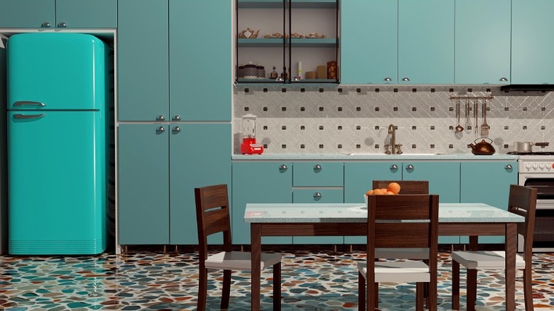 Teal kitchen with flat-face cabinets that have rounded silver handles.