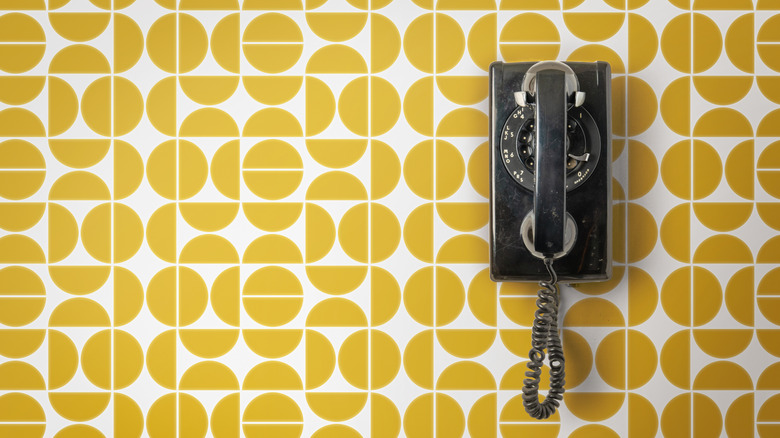 black telephone hanging on yellow geometric wallpaper