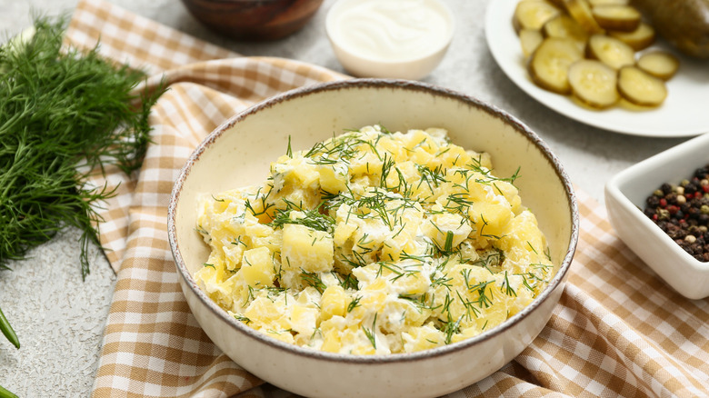 table set with potato salad with pickles and dill
