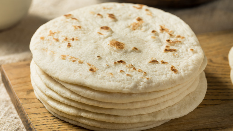 A stack of flour tortillas on a cutting board