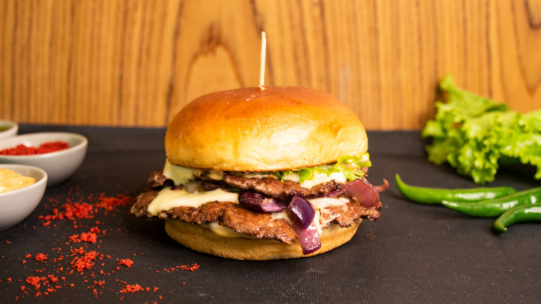 A smash burger styled alongside spices and peppers.