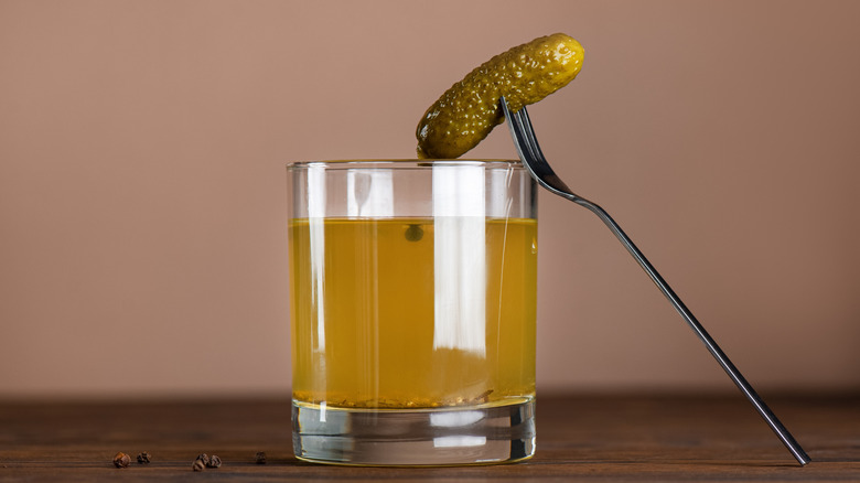 pickle on a fork on a glass of pickle juice