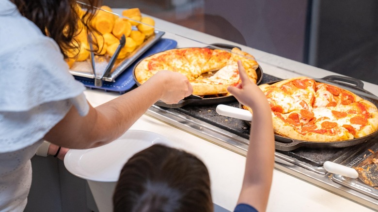Adult and child getting pizza off the buffet line at Golden Corral