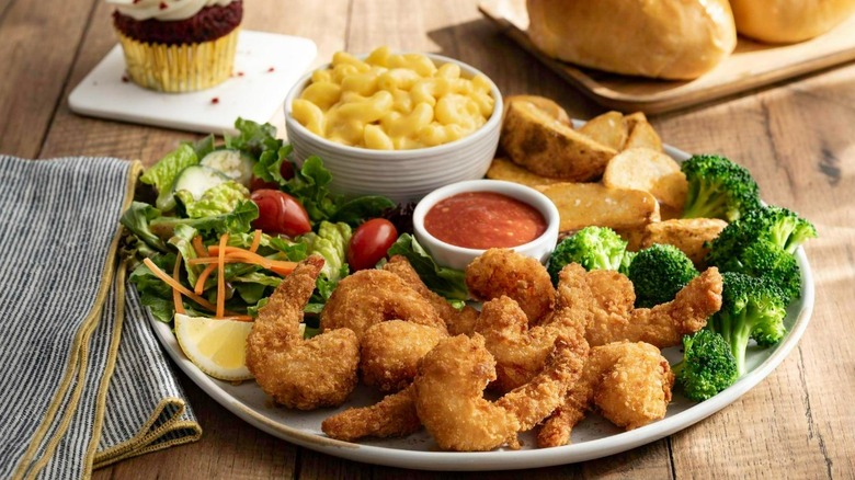 Plate of Golden Corral food filled with salad, fried shrimp, potato wedges, and macaroni and cheese
