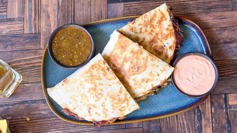 Gooey cheesesteak quesadillas on serving platter with dipping sauce