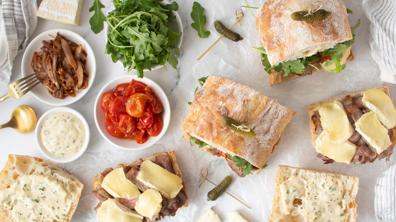 steak and cheese sandwiches with lettuce, tomato, and pickles