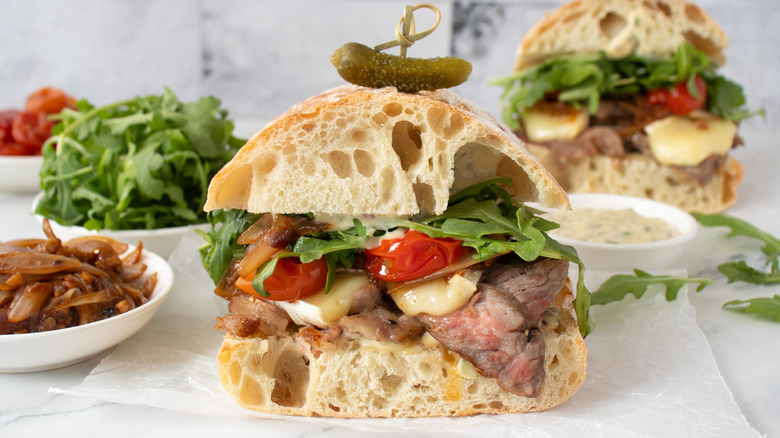 steak and cheese sandwich with lettuce, tomato, and pickle