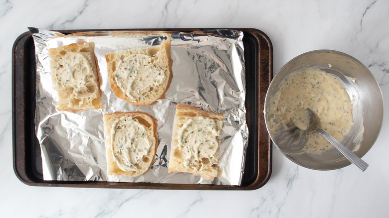 bread rolls with a creamy white spread on a foil-covered pan