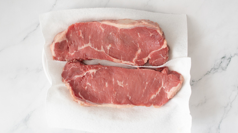 raw steaks on white paper towels