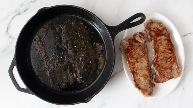 cooked steaks next to a black frying pan