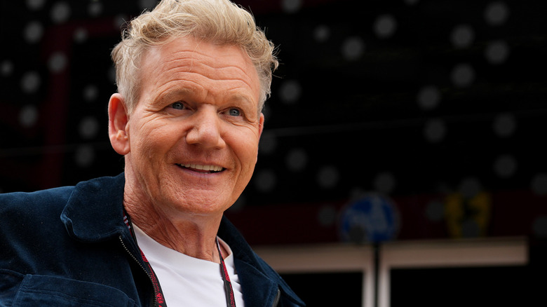 Gordon Ramsay smiling in a navy jacket with a white shirt underneath