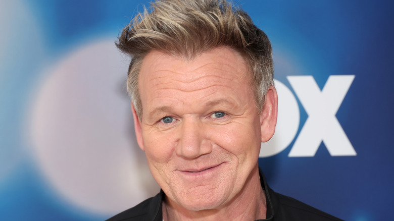 Chef Gordon Ramsay smiling with a blue backdrop behind him