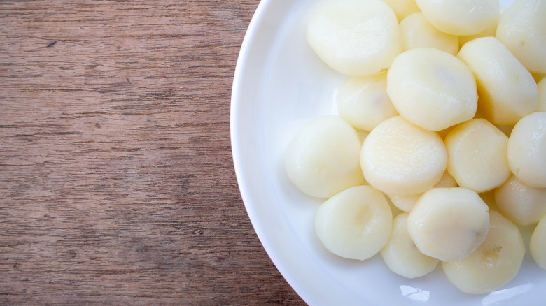 water chestnuts on a white plate on top of wooden table