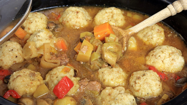 Beef stew containing dumplings with a wooden spoon in it