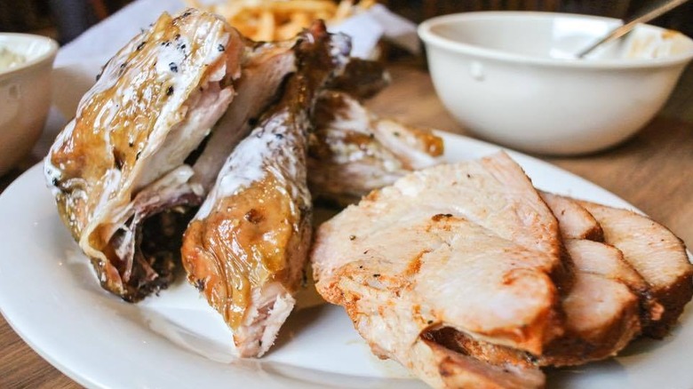 Chicken slathered in a white sauce on a white porcelain plate and a wooden table
