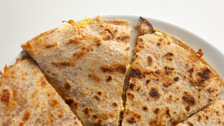 A crispy breakfast quesadilla with some scrambled eggs just peeking out of the edges