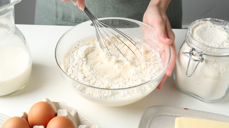Person making a dessert batter with eggs, flour, and butter