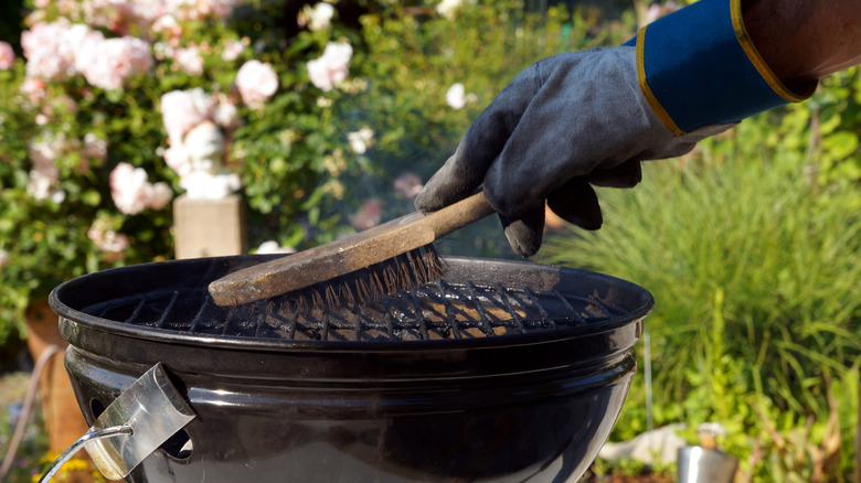 man cleaning grill with brush