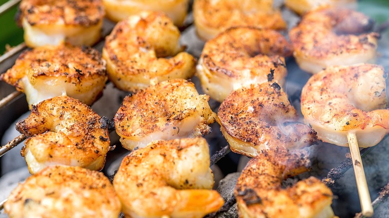 Close-up of seasoned shrimp skewers on grill.