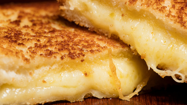 Grilled cheese sliced in half with melted cheese spilling out of the center.