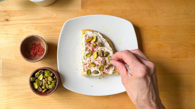 Focaccia bread slice with pistachios, chile flakes, and ricotta cheese on plate